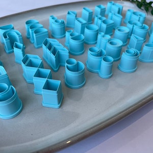 Puede incluir: Un juego de 25 cortadores de galletas de pl&aacute;stico azul claro en varias formas geom&eacute;tricas, incluyendo c&iacute;rculos, cuadrados, rect&aacute;ngulos y tri&aacute;ngulos.