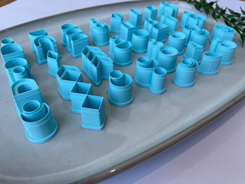 Puede incluir: Un juego de 25 cortadores de galletas de pl&aacute;stico azul claro en varias formas geom&eacute;tricas, incluyendo c&iacute;rculos, cuadrados, rect&aacute;ngulos y tri&aacute;ngulos.