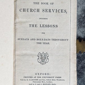May include: A vintage book titled "The Book of Church Services, Including The Lessons for Sundays and Holy-Days Throughout The Year." The book was printed in Oxford at the University Press in 1859.