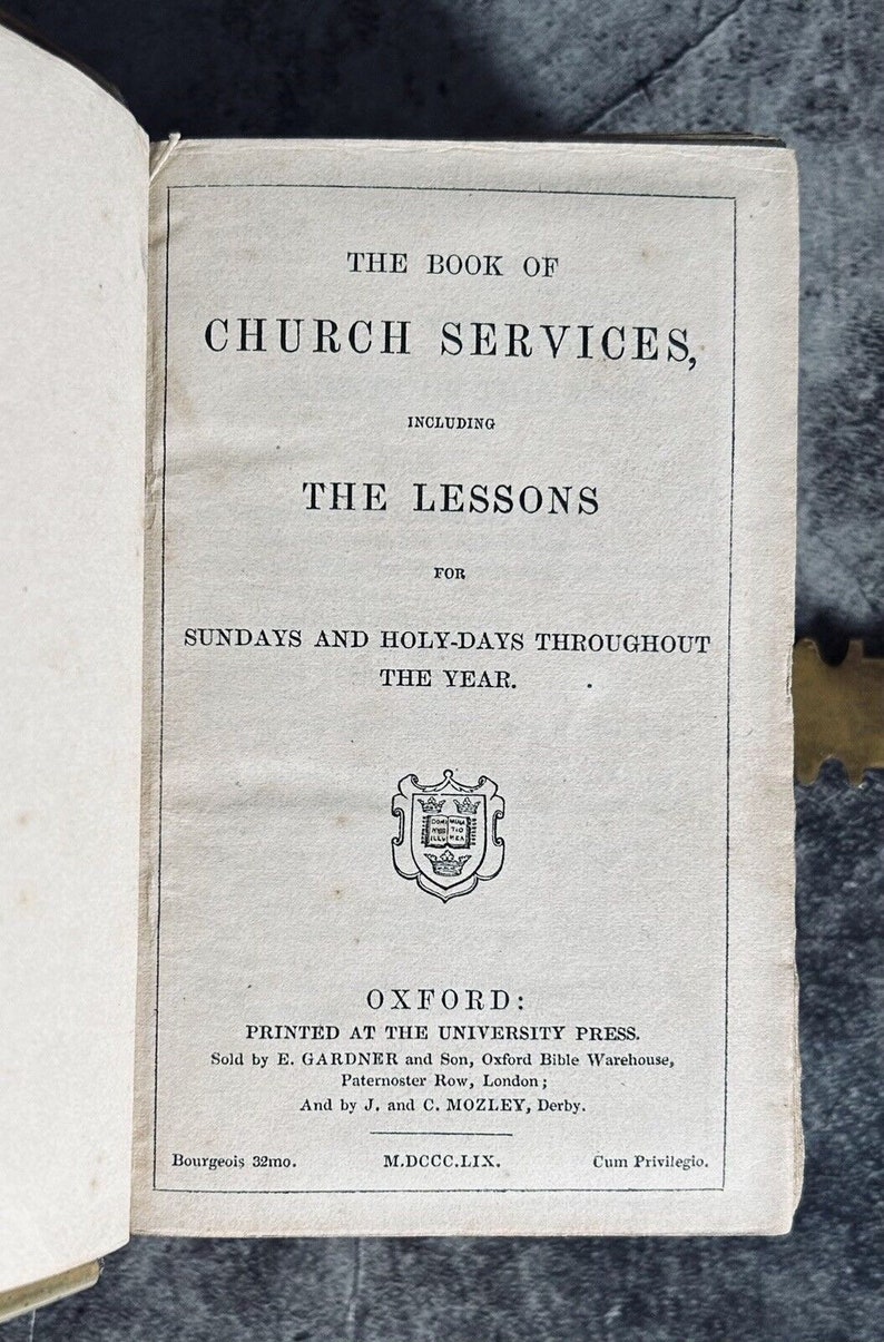 May include: A vintage book titled "The Book of Church Services, Including The Lessons for Sundays and Holy-Days Throughout The Year." The book was printed in Oxford at the University Press in 1859.