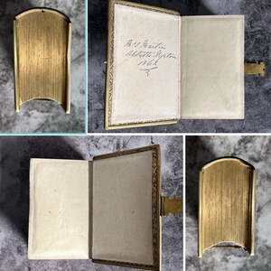 May include: A gold-colored photo album with a hinged clasp. The album is open to reveal a blank page with handwritten text: "Miss J. Austin, Abbotsleigh, Hiffton, 1862."