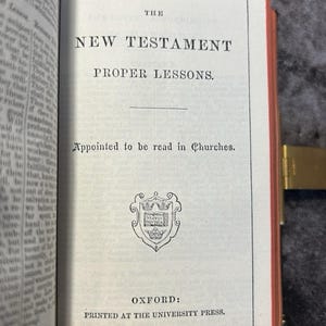May include: Open book displaying the title "THE NEW TESTAMENT PROPER LESSONS." The text "Appointed to be read in Churches" is below the title. The book is printed by Oxford University Press.