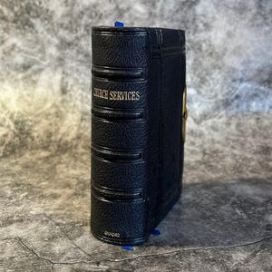 May include: A navy blue book with the words "CHURCH SERVICES" in silver lettering. The book has a textured cover and a blue ribbon bookmark. The word "OXFORD" is printed at the bottom.