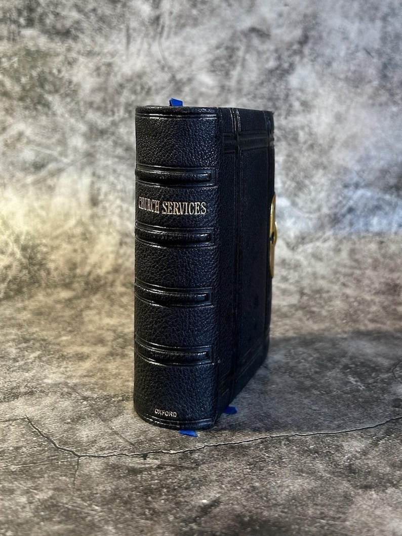May include: A navy blue book with the words "CHURCH SERVICES" in silver lettering. The book has a textured cover and a blue ribbon bookmark. The word "OXFORD" is printed at the bottom.
