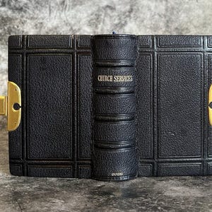 May include: A vintage black leather-bound book with gold accents and a clasp. The spine reads "CHURCH SERVICES" in gold lettering. The book is from Oxford.
