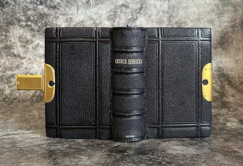 May include: A vintage black leather-bound book with gold accents and a clasp. The spine reads "CHURCH SERVICES" in gold lettering. The book is from Oxford.