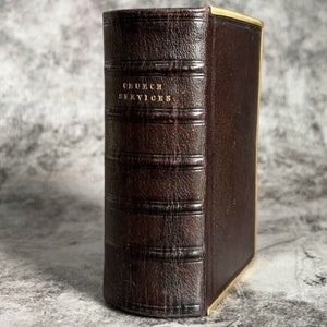 May include: A brown leather-bound book with gold lettering on the spine that reads "CHURCH SERVICES".