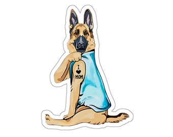 Peut inclure: Un chien berger allemand portant une chemise bleue avec un tatouage disant "J'aime maman" sur son bras.