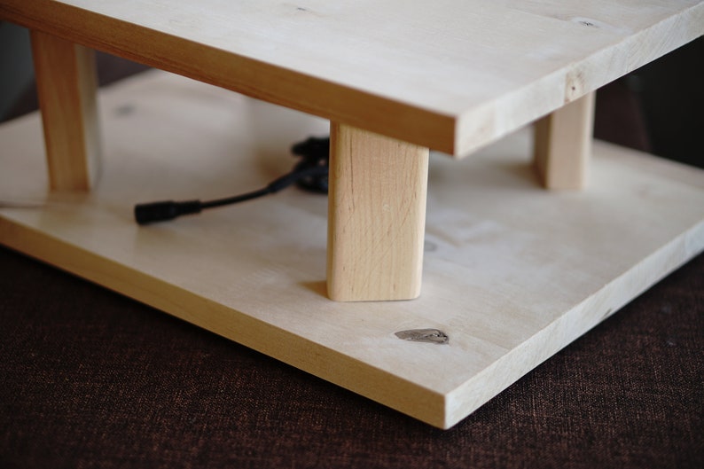 Pu&ograve; includere: Un supporto in legno con due ripiani, realizzato in legno chiaro. Il supporto ha un design semplice con quattro gambe e una forma rettangolare.