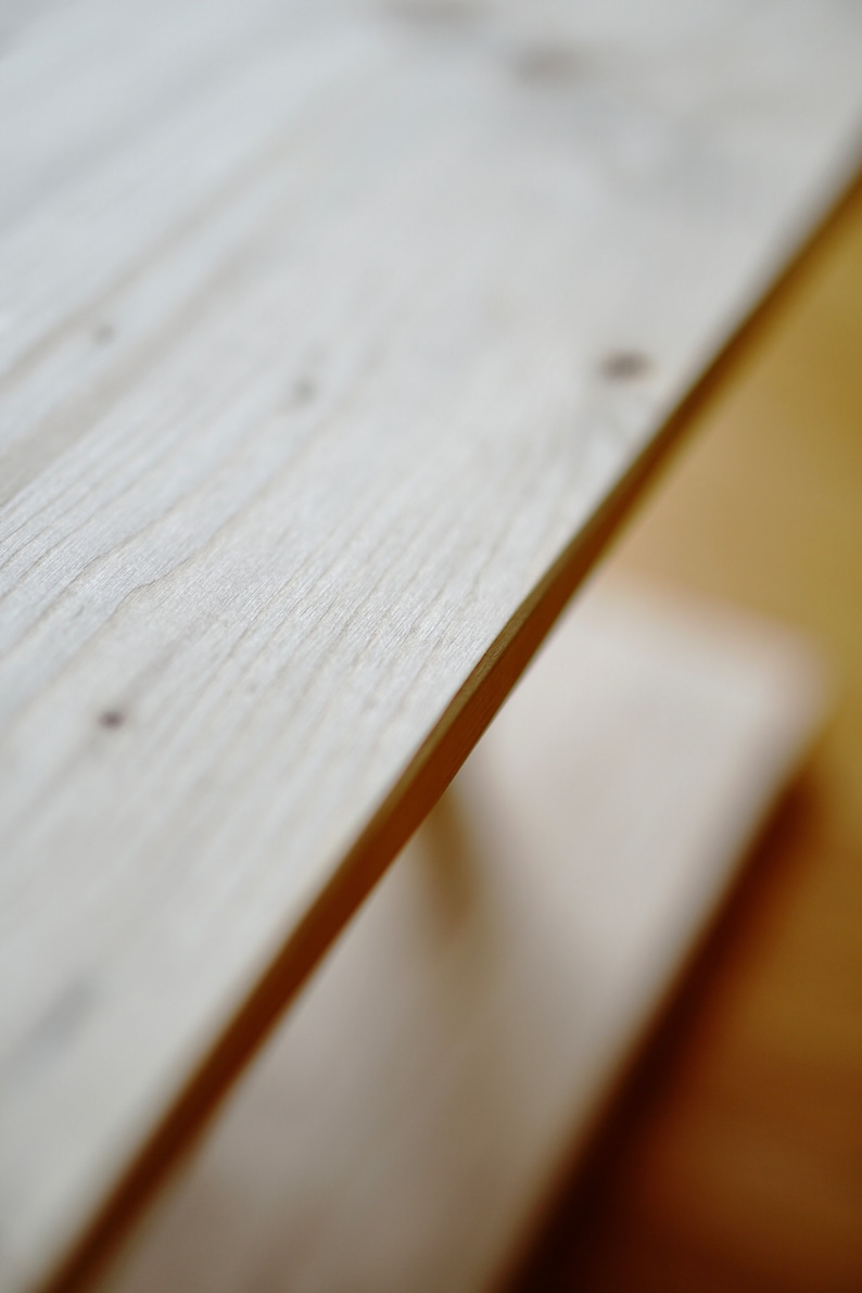 Pu&ograve; includere: Primo piano di uno scaffale in legno chiaro con una superficie liscia e leggermente strutturata. Lo scaffale &egrave; inclinato e sembra far parte di un mobile pi&ugrave; grande.