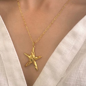 Puede incluir: Un collar de cadena dorada con un colgante de estrella de mar texturizado.