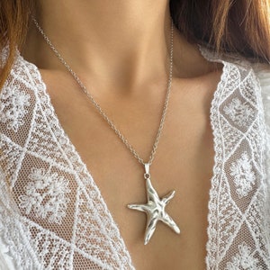 May include: A silver chain necklace with a textured silver starfish pendant.