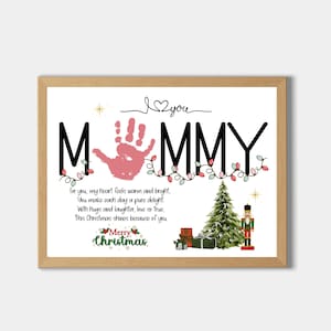 Pode incluir: Uma impressão emoldurada com a palavra "MOMMY" em letras pretas, uma impressão de mão rosa e decorações de Natal. A impressão inclui o texto "Merry Christmas" e um poema sobre amor e alegria.