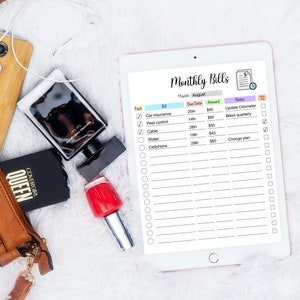 May include: A digital tablet displaying a monthly bills checklist with a list of bills, due dates, amounts, and notes. The checklist is for the month of August. The tablet is on a white fuzzy surface.