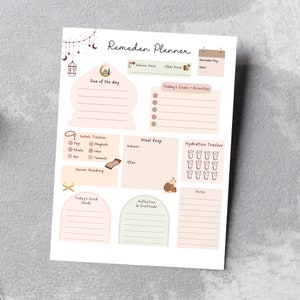 May include: A printable Ramadan planner with sections for daily goals, meal prep, hydration tracking, Quran reading, and reflection. The planner features a light pink and brown color scheme with illustrations of crescent moons, stars, and a mosque.