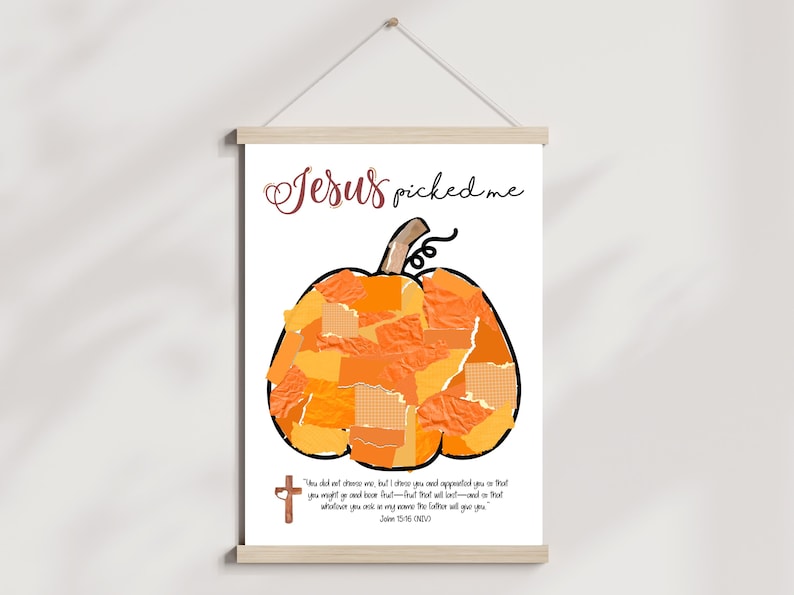 K&ouml;nnte beinhalten: Gerahmter Druck mit einem gro&szlig;en orangefarbenen K&uuml;rbis aus Papierst&uuml;cken. Der Text "Jesus picked me" steht oben, mit einem Bibelvers und einem Kreuz unten. Der Druck h&auml;ngt an einer Holzstange.