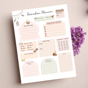 May include: A printable Ramadan planner with sections for daily goals, meal prep, hydration tracking, Quran reading, reflection, and gratitude. The planner features a light pink and green color scheme with illustrations of a mosque, a prayer rug, and a glass of water.