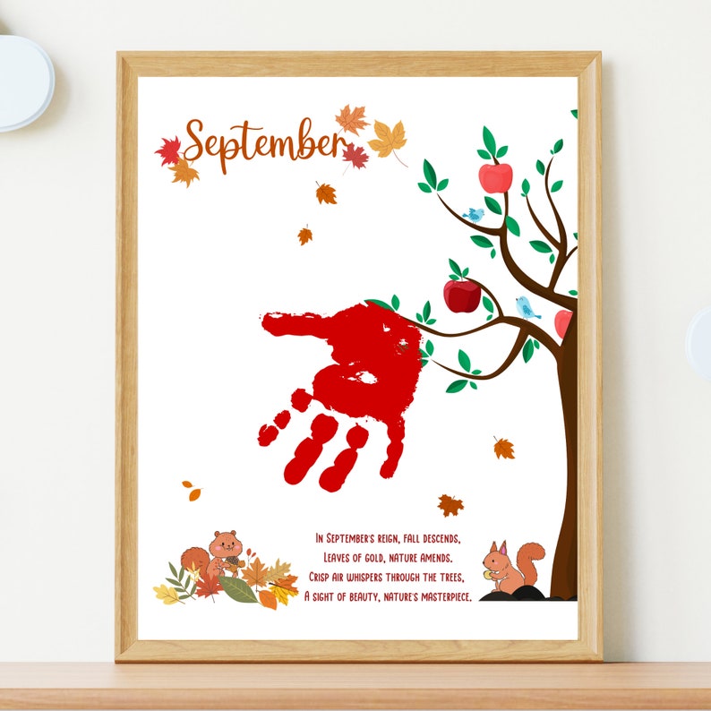 May include: A framed print with a red handprint on a tree with green leaves and red apples. The text reads 'September' and 'In September's reign, fall descends, Leaves of gold, nature amends. Crisp air whispers through the trees, A sight of beauty, nature's masterpiece.'