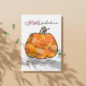 K&ouml;nnte beinhalten: Eine wei&szlig;e Karte mit einer K&uuml;rbisillustration aus orangefarbenen und gelben Papierst&uuml;cken. Der Text "Jesus picked me" ist in einer Schreibschrift geschrieben. Ein kleines Kreuz und ein Bibelvers sind ebenfalls vorhanden.