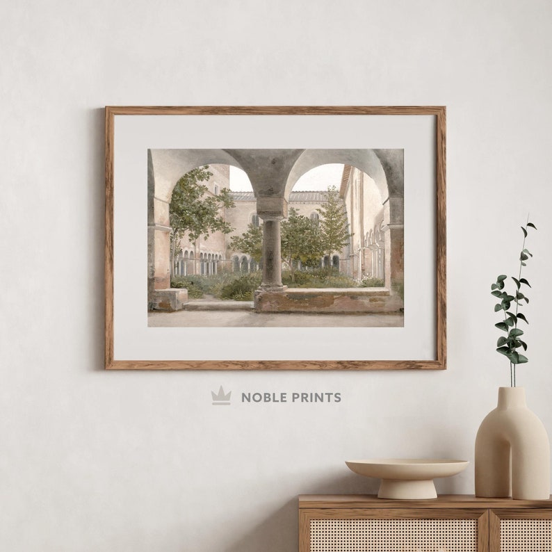 May include: A framed photograph of a courtyard with arched walkways and lush greenery. The courtyard is surrounded by stone walls and columns, creating a sense of tranquility and peace.