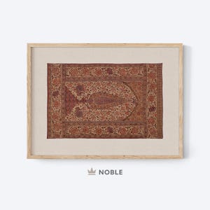 May include: A framed print of a vintage rug with a floral pattern in shades of red, brown, and cream. The rug has a central design of a stylized leaf or flower.