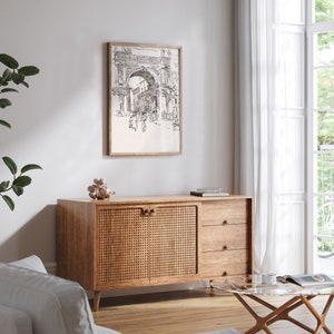 K&ouml;nnte beinhalten: Ein Schrank aus Holz mit zwei T&uuml;ren aus geflochtenem Schilfrohr und drei Schubladen. Der Schrank hat eine hellbraune Farbe und steht auf einem Holzboden. Ein Schwarzwei&szlig;-Druck eines Torbogens h&auml;ngt an der Wand &uuml;ber dem Schrank.