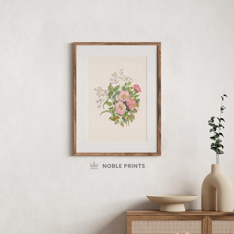 K&ouml;nnte beinhalten: Eine gerahmte botanische Illustration von rosa und wei&szlig;en Bl&uuml;ten mit gr&uuml;nen Bl&auml;ttern. Der Druck ist auf cremefarbenem Hintergrund und tr&auml;gt den Text "NOBLE PRINTS" unten.