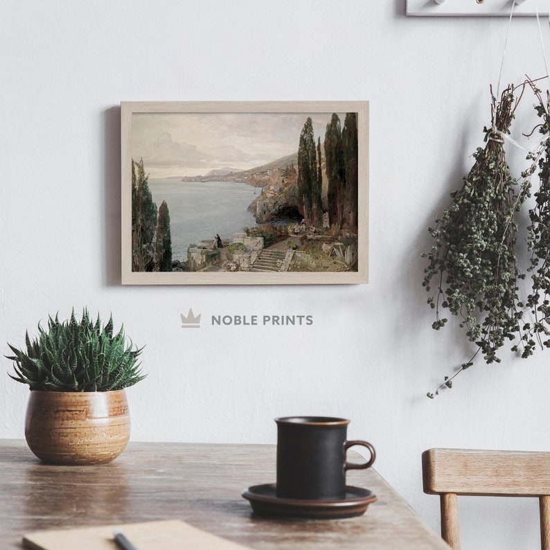 May include: A framed painting of a seascape with a stone path leading to a small building. The painting is in a light wood frame and is hanging on a white wall.