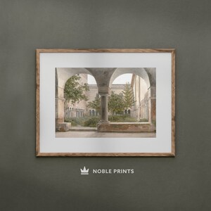 May include: A framed photograph of a courtyard with arched walkways and lush greenery. The courtyard is surrounded by stone walls and columns, creating a sense of tranquility and peace.