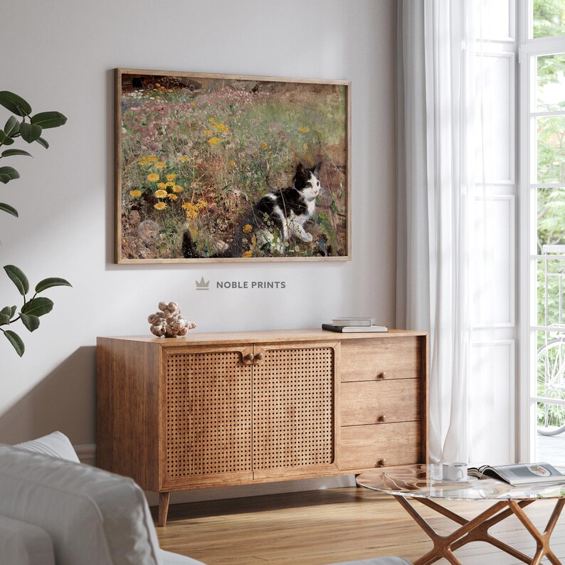 May include: A black and white cat sits in a field of yellow and white wildflowers. The cat is looking to the right of the image. The background is a blurred green field.