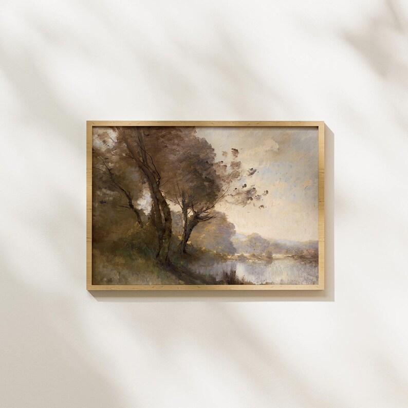 Puede incluir: Pintura de paisaje enmarcada que representa una serena escena junto al agua. La obra de arte representa &aacute;rboles con follaje marr&oacute;n y una masa de agua bajo un cielo nublado. El marco es de color marr&oacute;n claro.