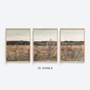 May include: A set of three framed landscape paintings depicting a field of wildflowers with a distant mountain range in the background. The paintings are in a muted color palette of browns, greens, and blues.