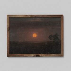 May include: A framed print of a landscape with a large orange moon in the sky. The moon is surrounded by a dark, cloudy sky. A single tree stands in the foreground, silhouetted against the moon.