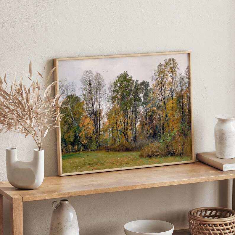 Op de afbeelding: Een ingelijste print van een landschapssc&egrave;ne met bomen in verschillende tinten groen en geel. De bomen staan op een veld met een lichtblauwe lucht op de achtergrond.