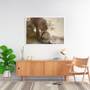 Puede incluir: Una pintura de paisaje enmarcada representa &aacute;rboles cerca de un cuerpo de agua. La obra de arte, en un marco blanco, presenta tonos apagados de marr&oacute;n, verde y beige. La pintura cuelga sobre un mueble de madera con una l&aacute;mpara, una silla y objetos decorativos.