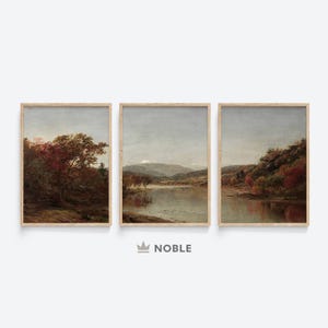 May include: A set of three framed landscape paintings depicting a river scene with trees and mountains in the background. The paintings are in a muted color palette of browns, greens, and blues.