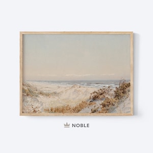 Puede incluir: Una pintura de acuarela enmarcada que representa una escena de playa con dunas de arena y un océano azul en la distancia. El cielo es de un azul claro con algunas nubes. La pintura está en un marco de madera claro.