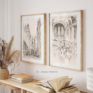May include: Two black and white framed prints of cityscapes. The print on the left shows a street scene with tall buildings. The print on the right shows a crowded interior space with a vaulted ceiling.