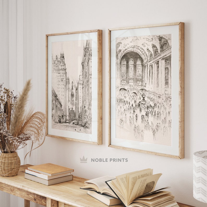 May include: Two black and white framed prints of cityscapes. The print on the left shows a street scene with tall buildings. The print on the right shows a crowded interior space with a vaulted ceiling.