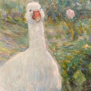 May include: A white goose with a red beak stands in a field of green and blue brush. The goose is looking directly at the viewer.