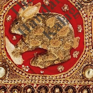 May include: A red fabric square with a gold embroidered rabbit design. The rabbit is surrounded by a gold border with small gold beads. The fabric has a gold and red border with small gold beads.
