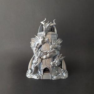 May include: A silver 3D printed tower with four dragons sculpted around it. The tower has a small entrance at the base.
