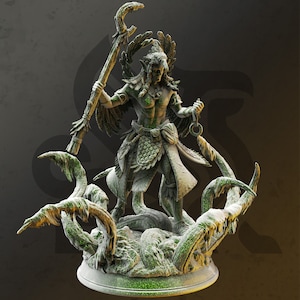 Puede incluir: Una figura verde y marrón de una figura humanoide alada sosteniendo un bastón. La figura está de pie sobre una base de enredaderas y hojas retorcidas.