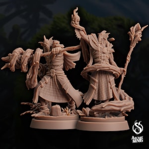 May include: Two detailed miniature figures of humanoid figures with bird-like features, wearing robes and holding staffs. The figures are posed in a dynamic fashion, with one figure holding a staff aloft and the other figure holding a staff in a more relaxed pose. The figures are painted in a light brown color and are set against a dark background.