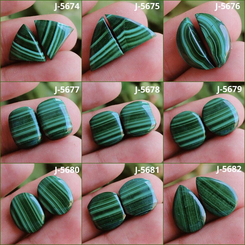 May include: A collection of nine pairs of polished malachite gemstones, each displaying unique patterns of dark and light green bands. The stones vary in shape, including triangles, ovals, and teardrops. Each pair is labeled with a "J-56" series number.