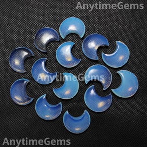 Puede incluir: Una colección de gemas en forma de media luna azul opalina. Las gemas tienen una calidad translúcida con un patrón sutil y moteado. El texto "AnytimeGems" es visible en la imagen.