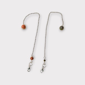 May include: Two silver-toned metal chains, each featuring a small spherical bead at one end and a larger spherical bead near the other end, which terminates in a lobster claw clasp. One chain has orange-toned beads, while the other has green-toned beads.