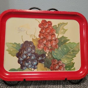 May include: Red metal serving tray with a white background and a painted image of grapes. The grapes are red and purple and are arranged in clusters on a vine.