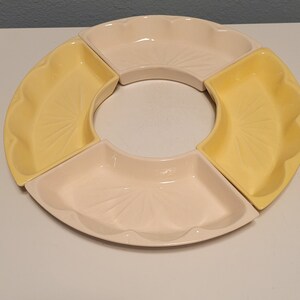 May include: A set of four ceramic serving dishes in a circular shape. Two of the dishes are yellow and two are white. The dishes have a scalloped edge and a decorative pattern.