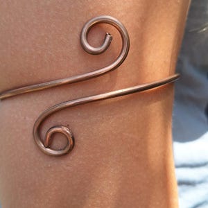 May include: A copper wire arm bracelet with a double swirl design.